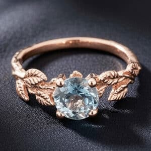 Nature-inspired solitaire aquamarine engagement ring with four prongs and leaf accents in rose gold.