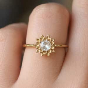 Close-up detail of a sunflower ring with a natural rose cut diamond and textured gold petals.