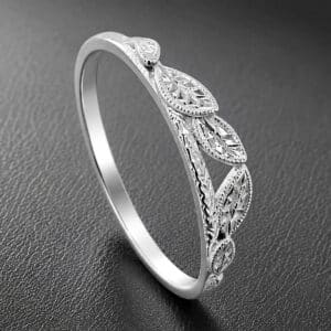 Nature-inspired curved wedding band featuring hand-carved leaf motifs, milgrain edges, and a polished 14K white gold finish.