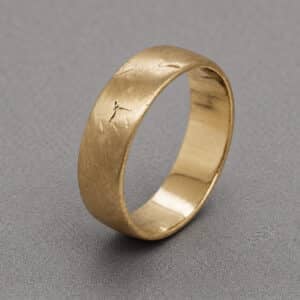 Angled view of textured men’s wedding band with raw matte gold finish and rustic surface by OroSpot