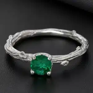 Green emerald nature-inspired engagement ring in white gold with hand-carved tree bark texture and leaf details.
