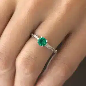 Tree branch emerald engagement ring handcrafted in gold with bark texture and leaf accents.