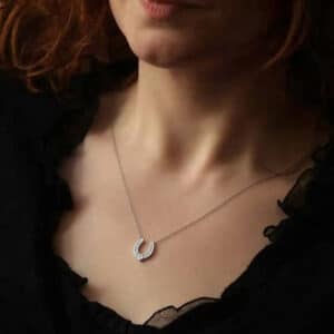 Lucky horseshoe necklace in 14K white gold featuring round brilliant diamonds and a princess-cut center diamond on a delicate chain.