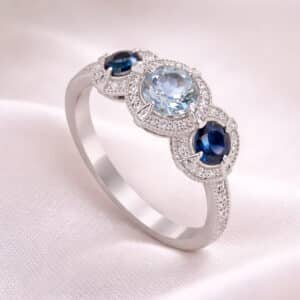 Modern aquamarine sapphire ring with diamond halos, half diamond band, and polished white gold setting
