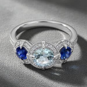 Three-stone aquamarine and sapphire engagement ring with diamond halo accents and pavé white gold band by OroSpot.