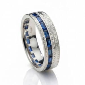 Vintage-inspired men's wedding band with channel-set blue sapphire baguettes on a hand-engraved 14K white gold band with milgrain edges.