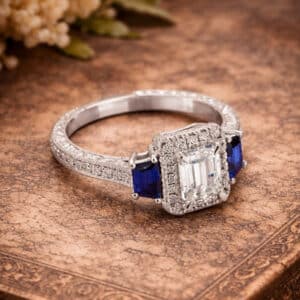 Art Deco emerald cut diamond sapphire ring with lab-grown center diamond, trapezoid sapphires, diamond halo, and vintage inspired detailing