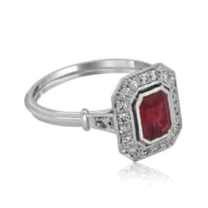 Side profile of Art Deco emerald cut ruby and diamond engagement ring with filigree under-gallery.
