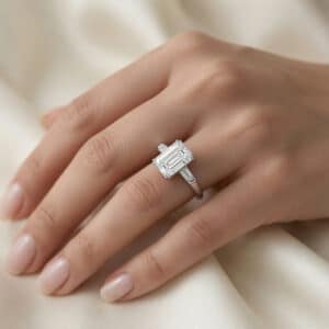 Close-up detail of an emerald-cut three-stone engagement ring with Art Deco-inspired geometry and tapered baguette diamonds.