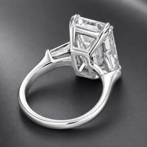 Side profile of an emerald-cut diamond engagement ring featuring split claw prongs and tapered baguette side stones.