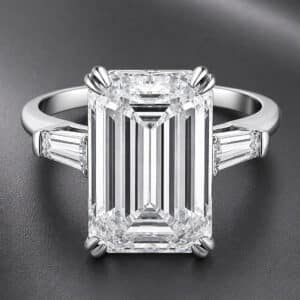 Three-stone engagement ring featuring an 8-carat emerald-cut lab-grown diamond with tapered baguette side diamonds and split claw prongs.