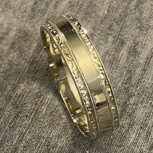 Close-up of hand engraving process on high-polish Art Deco men’s wedding band in white unplated 18K gold.