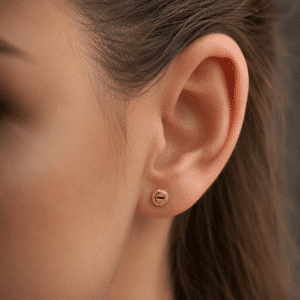 Woman wearing small screw-inspired 14K gold stud earrings by OroSpot for size reference.