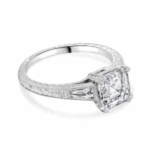 Vintage engagement ring featuring an Asscher cut diamond, set in an ornate band with intricate detailing.