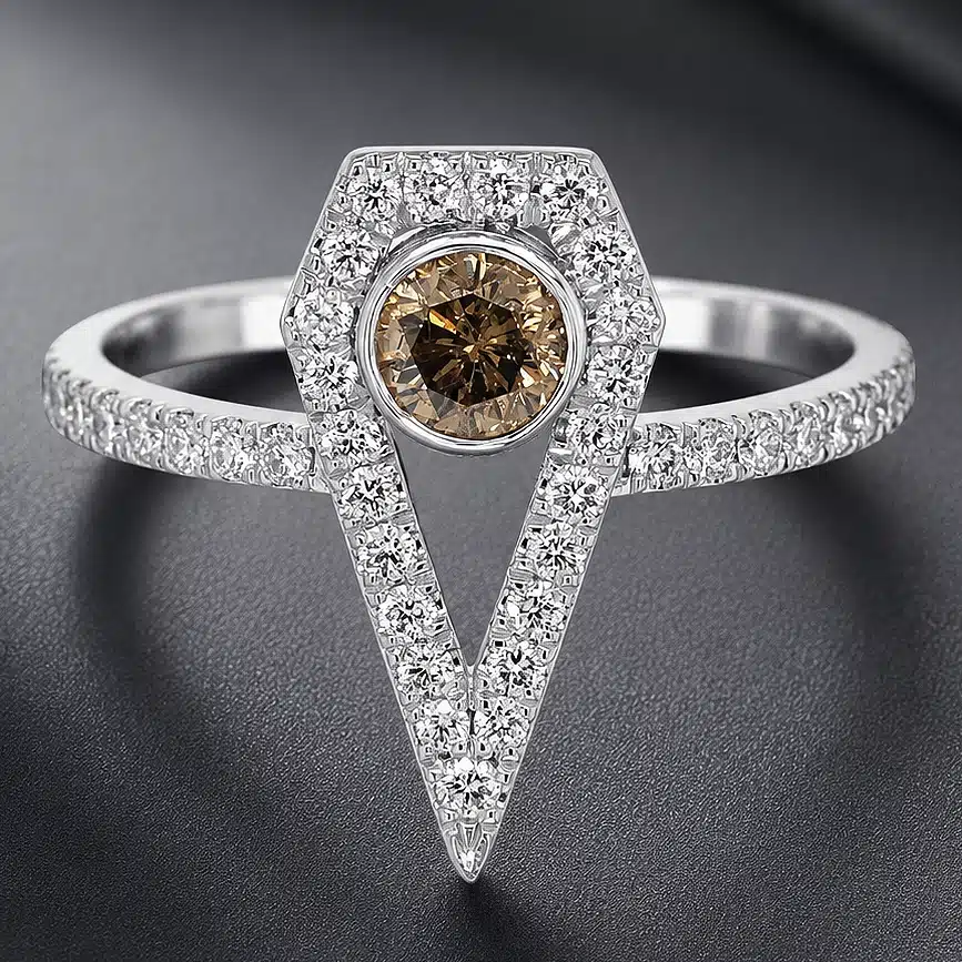 Art Deco-inspired engagement ring featuring a round brown diamond in a geometric shield-shaped diamond halo with a pavé diamond band in white gold.