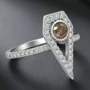 White gold engagement ring with a round brown diamond center stone, shield-shaped diamond halo, and pavé-set diamond shank.