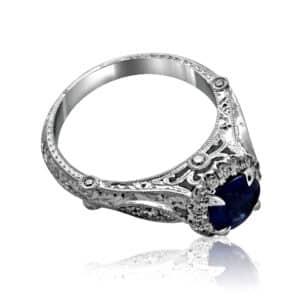 Art Deco sapphire engagement ring with 1.5ct round blue sapphire, diamond halo, and hand engraving in 14K white gold.