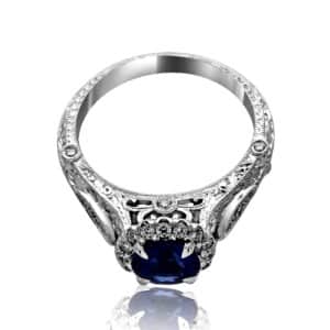 Hand-engraved sapphire engagement ring with round blue sapphire, filigree patterns, and milgrain edges.