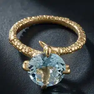 Nature-inspired eagle talon ring with a round aquamarine gemstone, sculptural bird claw setting, and organic gold design.