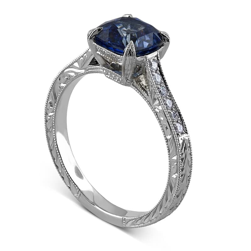 Antique cushion sapphire engagement ring with hand engraving and diamond accents.