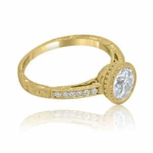 Bezel-set Art Deco engagement ring with vintage hand engraving and pavé diamonds in yellow gold.