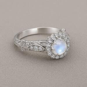 Close up of cabochon moonstone ring with diamond accents showing hand engraving and milgrain details by OroSpot