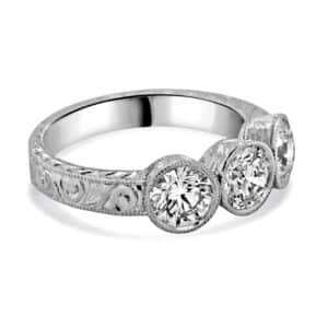 side profile of low-profile hand-engraved three-stone bezel ring in platinum, wheat engraving along the sides — OroSpot