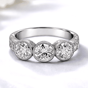 Vintage bezel three stone engagement ring in white gold with round diamonds, hand engraved scroll detailing, milgrain halos, past present future antique heirloom style by OroSpot.
