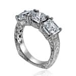Vintage-inspired lab diamond engagement ring featuring a euro shank for balance and hand-engraved scrolls; prong-set three-stone layout with Asscher sides. OroSpot