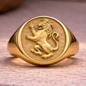 Yellow gold lion signet ring with raised heraldic crest on textured face.