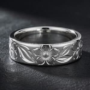 White gold men's wedding band with deep-relief Hawaiian floral engraving, botanical scrollwork, polished borders, and comfort-fit design.